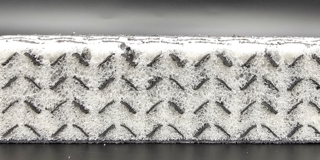 Dargestellt ist ein Querschnitt eines Schaumblock. Der Block besteht aus einer 3D-gedruckten Füllstruktur, die mit Schaum ausgefüllt wurde.